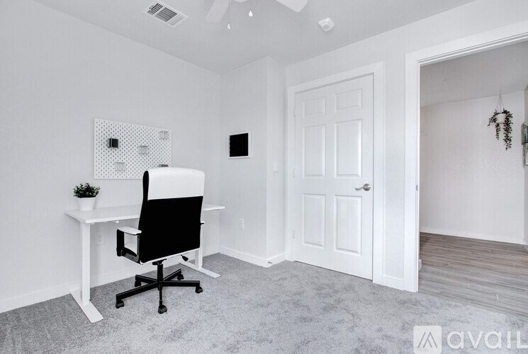A white desk with a black chair in a room with a white door.