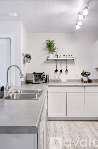 A kitchen with white cabinets and a stainless steel sink.