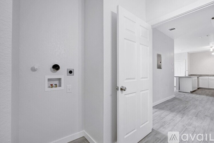 A white door is in a room with a white wall and a white floor.