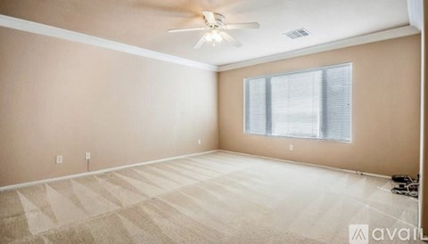 A room with a fan, carpet, and a window.