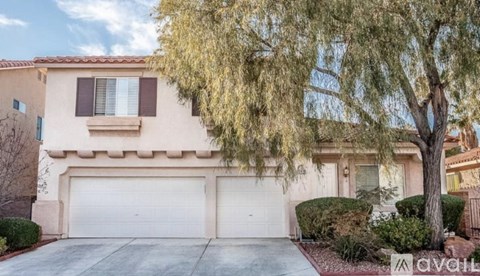 A beige house with a white garage door and a tree in front.