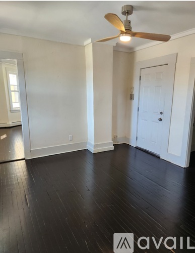 A room with a ceiling fan and wooden floors.
