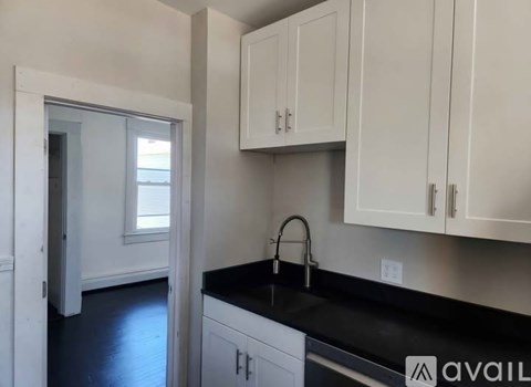 A kitchen with white cabinets and a black countertop.