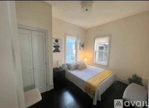 A bedroom with a bed, a chair, and a window.