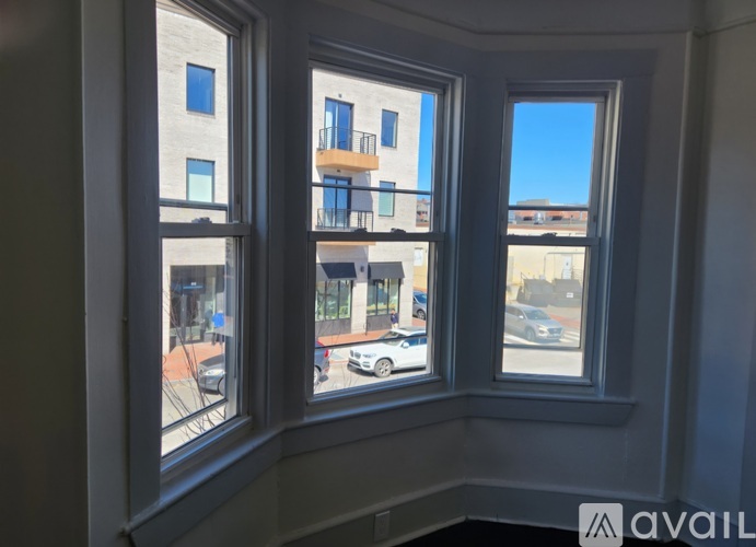 Three windows overlooking a street with cars and buildings.