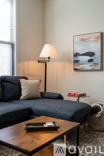 A living room with a blue couch, a wooden coffee table, and a lamp.
