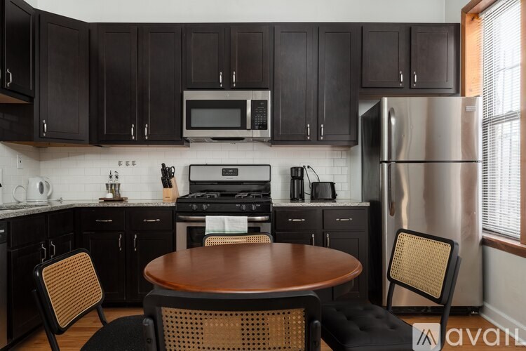 A kitchen with a table and chairs in front of a refrigerator.