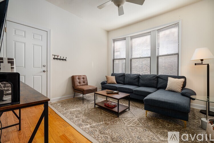 A living room with a grey couch, a brown chair, and a wooden table.