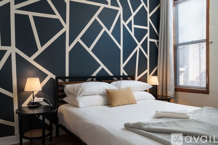 A bedroom with a bed, a lamp, and a geometric wallpaper.