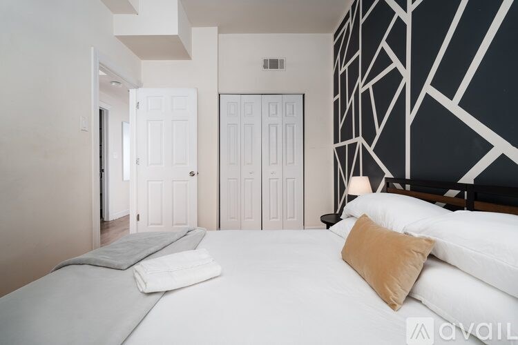 A bedroom with a large bed and a black and white geometric wallpaper.