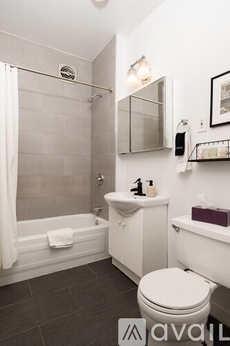 A white toilet sits in a bathroom with a white tub and sink.