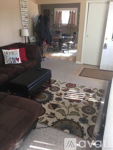 A living room with a brown couch and a rug with a floral pattern.