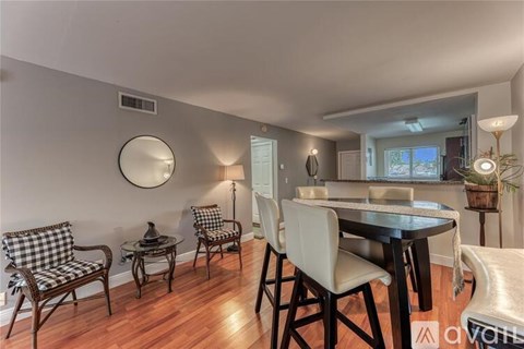 A dining room with a round mirror and a table with chairs.