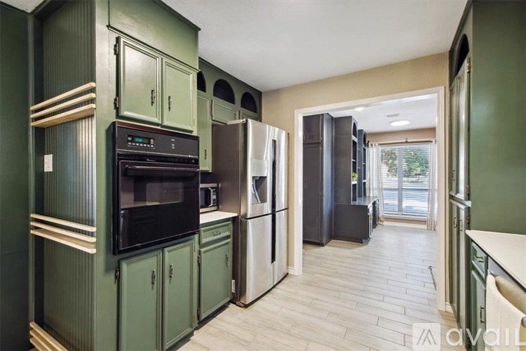 A kitchen with green cabinets and a black oven.