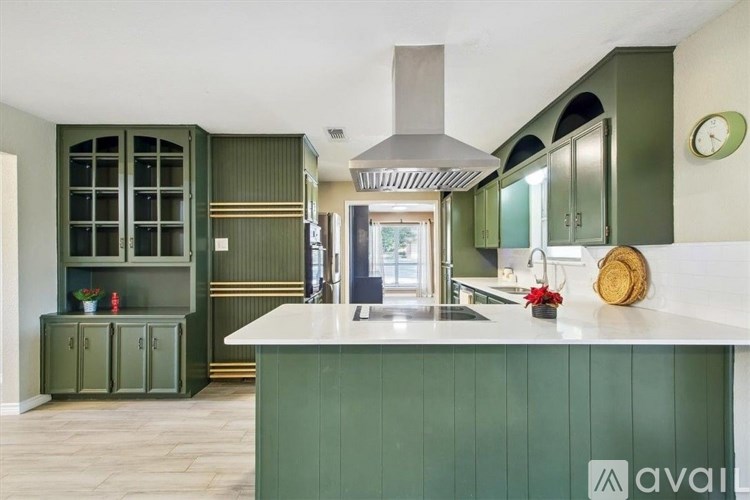 A kitchen with green cabinets and a white countertop.