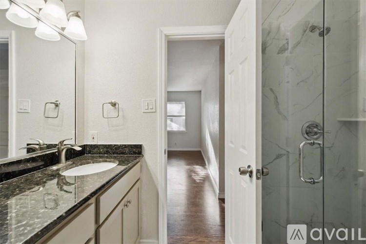 A bathroom with a marble countertop and a walk-in shower.