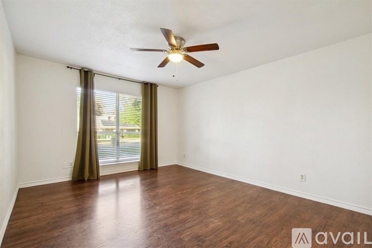 A room with a ceiling fan and wooden flooring.