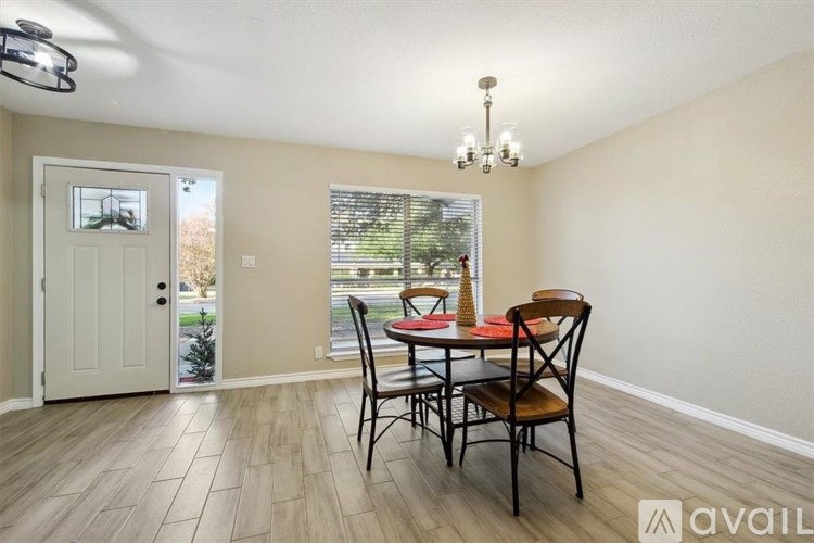 A dining room with a table set for two and a chandelier.