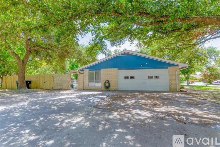 A blue and white building with a garage door is surrounded by trees.