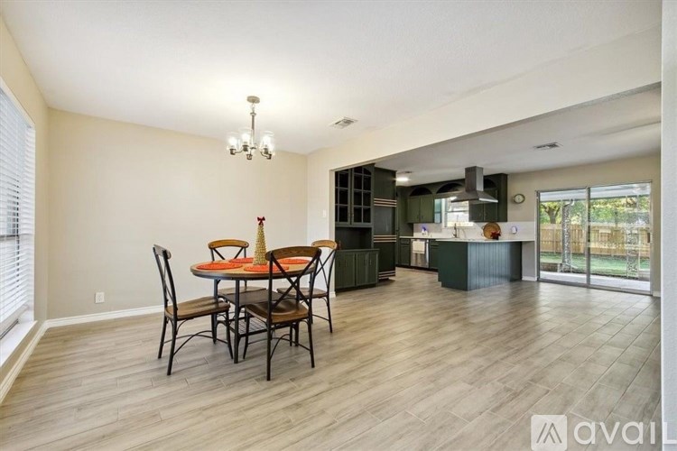 A dining room with a table set for six and a kitchen area in the background.
