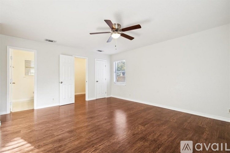 A room with a ceiling fan and wooden flooring.
