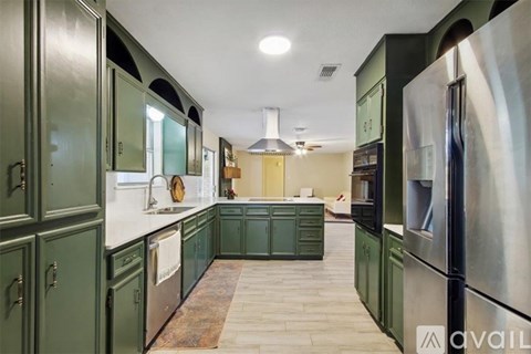 A kitchen with green cabinets and a wooden floor.