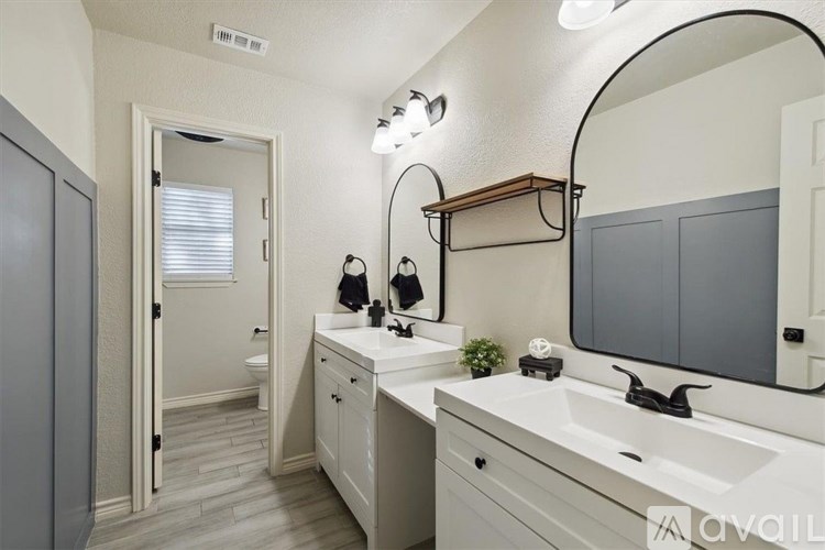 A bathroom with a white sink and a round mirror.