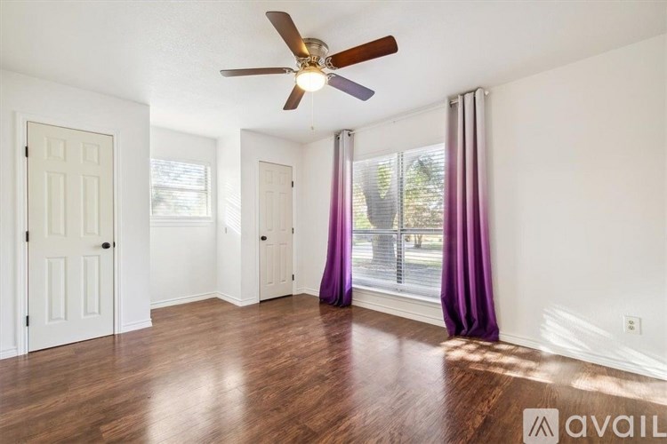 A room with a ceiling fan and wooden floors.