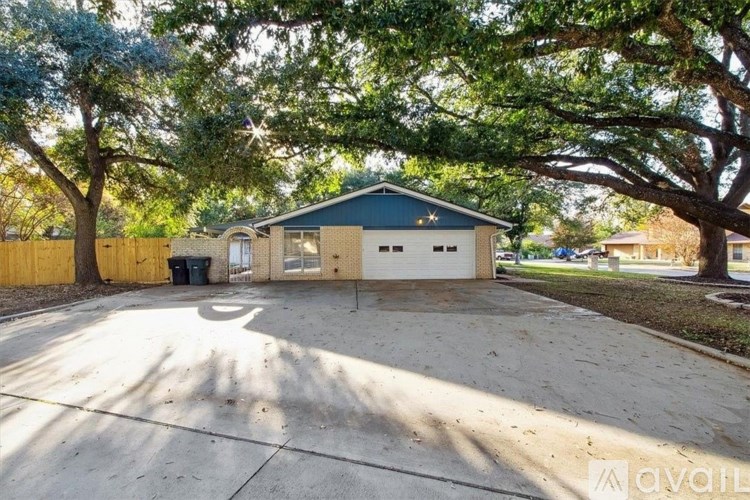 A house with a driveway and trees in front of it.
