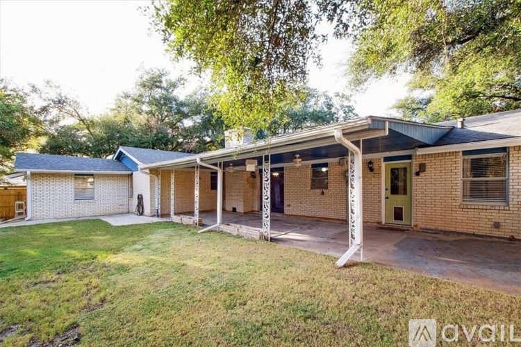 A house with a front yard and a tree in the background.