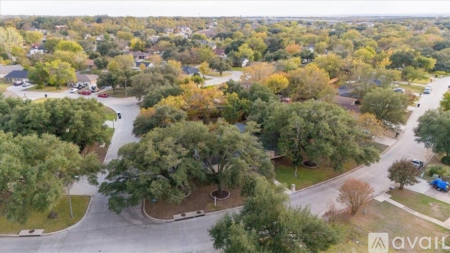 A bird's eye view of a suburban neighborhood with a mix of trees and houses.