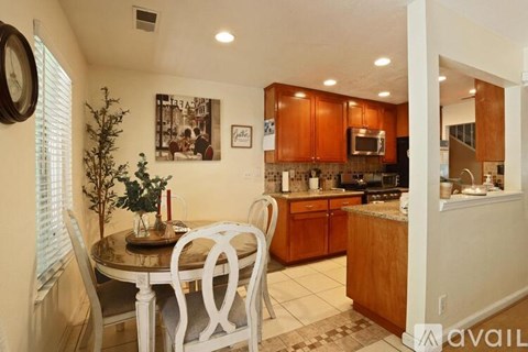 A kitchen with a table and chairs in the foreground and a framed picture on the wall.