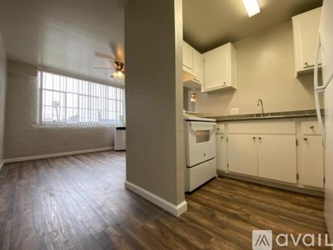 A kitchen with white cabinets and a wooden floor.