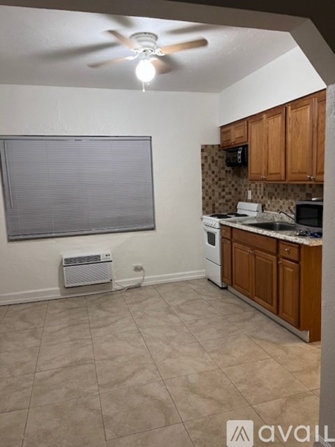 A kitchen with a fan and a window with blinds.
