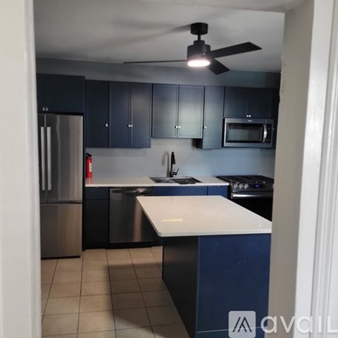A kitchen with a white counter top and a ceiling fan.