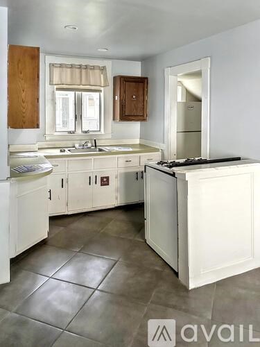 A kitchen with white cabinets and a tile floor.