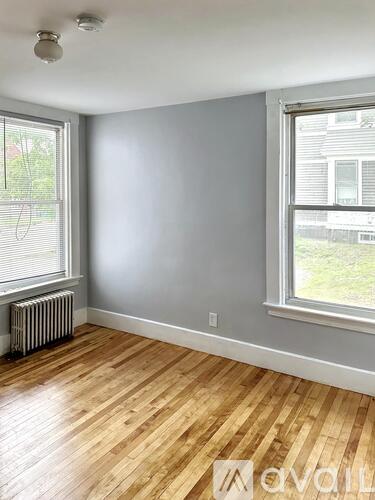 A room with wooden floors and two windows.