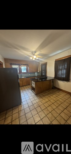 A kitchen with a black refrigerator and brown cabinets.