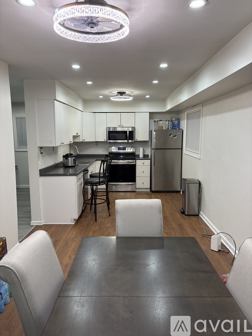 A kitchen with a black table and white chairs.