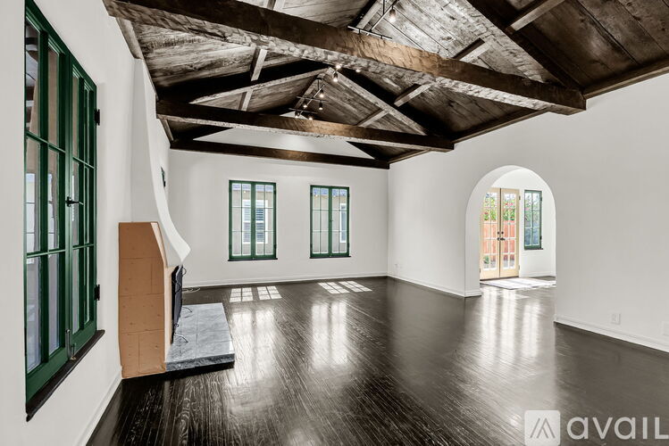 A spacious room with wooden floors and a high ceiling with exposed beams.