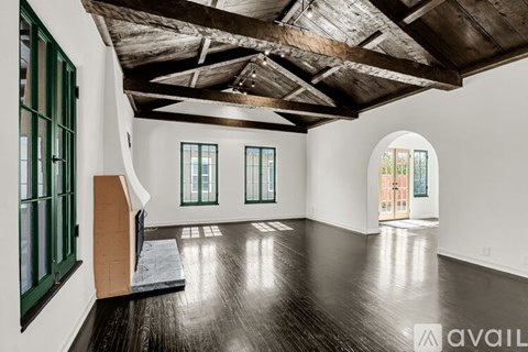 A spacious room with wooden floors and a high ceiling with exposed beams.