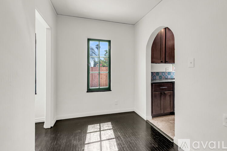 A room with a large window and a view of a fence and trees outside.