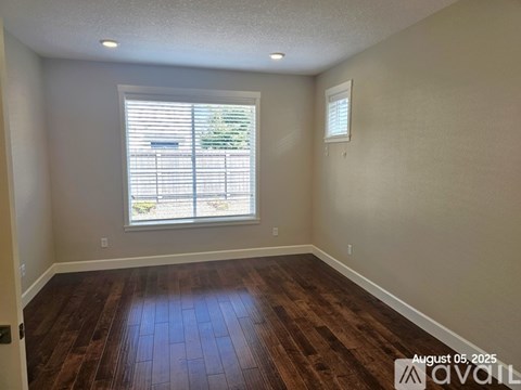 A room with wooden floors and a window with blinds.