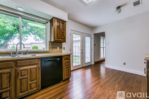 A kitchen with wooden cabinets and a black dishwasher.