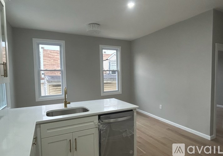 A kitchen with a sink and cabinets under a window.