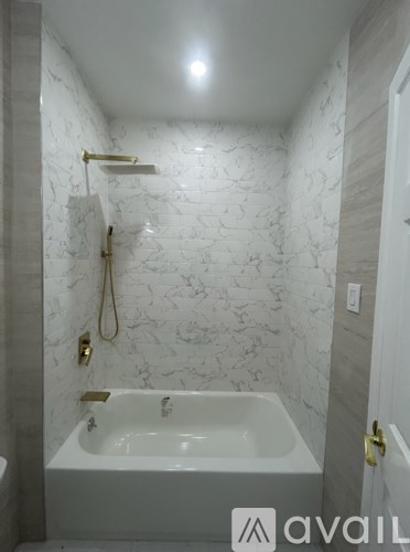 A white bathroom with a marble wall and a bathtub.