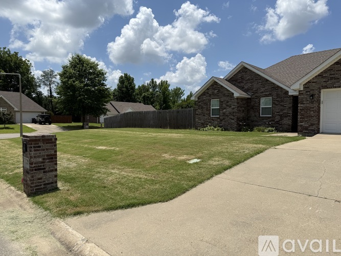 A house with a fence and a stone pillar in front of it.