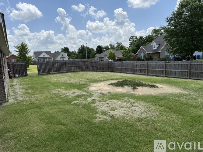 A backyard with a fence and a grassy area.