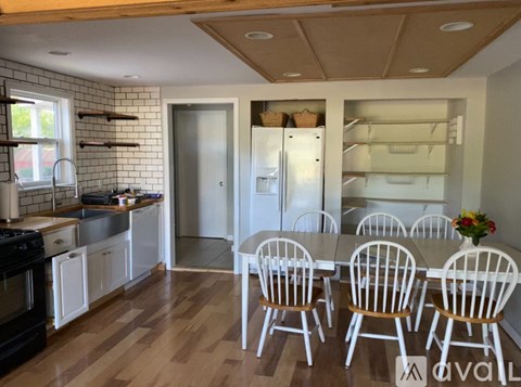 A kitchen with white cabinets and a wooden floor.