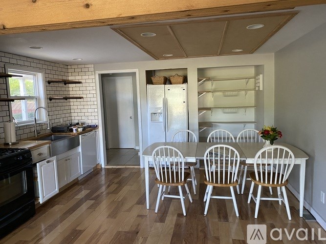 A kitchen with white cabinets and a wooden table.